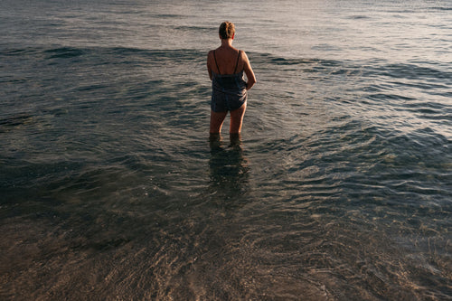 Lady in swimming suit standing at the sea shore at dusk